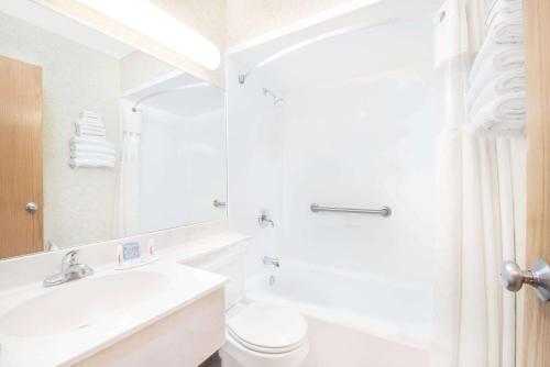 Baño blanco con lavabo y aseo en Days Inn by Wyndham West Rapid City, en Rapid City