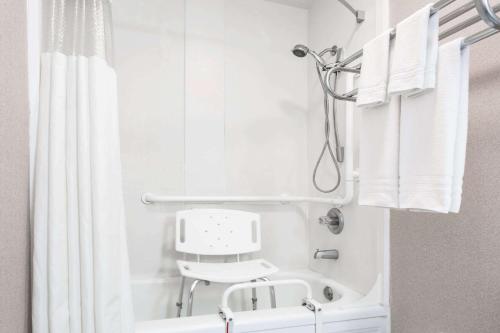 y baño con ducha blanca y silla. en Travelodge by Wyndham La Grande, en La Grande