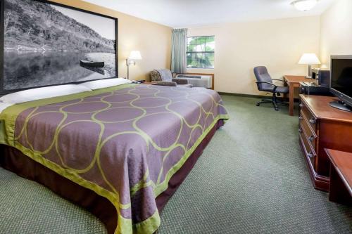 a hotel room with a large bed and a desk at Super 8 by Wyndham Pine Bluff in Pine Bluff
