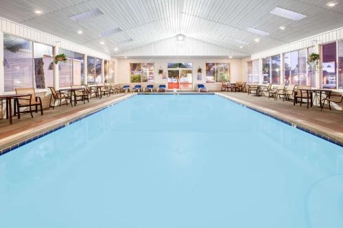 una gran piscina con mesas y sillas en Super 8 Beachfront by Wyndham Mackinaw City, MI, en Mackinaw City