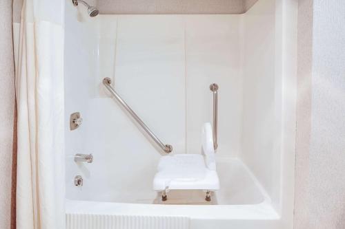 a white bath tub with a white seat in a bathroom at Super 8 Beachfront by Wyndham Mackinaw City, MI in Mackinaw City