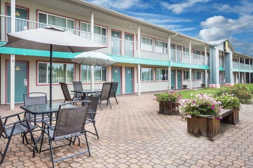 eine Terrasse mit einem Tisch, Stühlen und einem Sonnenschirm in der Unterkunft Super 8 by Wyndham Quesnel BC in Quesnel