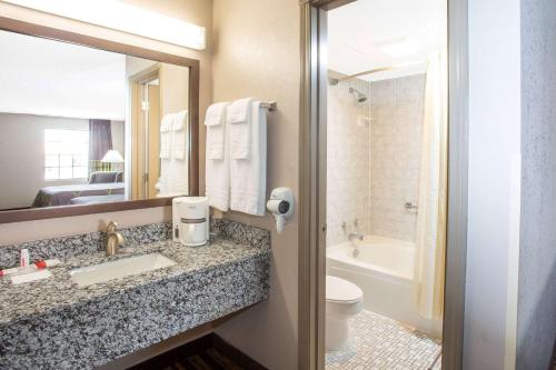 a bathroom with a sink and a toilet and a mirror at Super 8 by Wyndham Springdale AR in Springdale