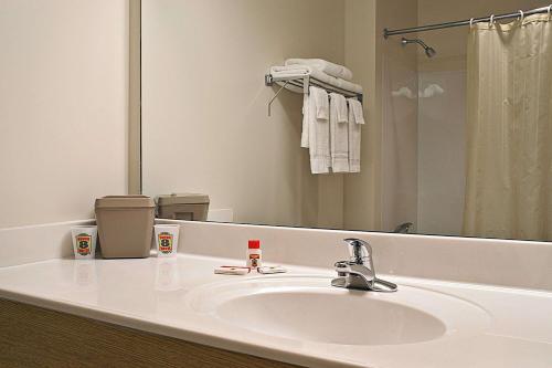 a bathroom sink with a mirror and a towel rack at Super 8 by Wyndham Ava in Ava