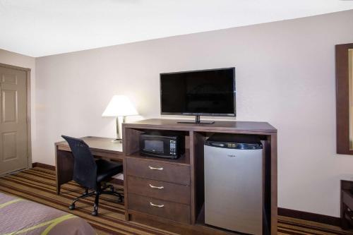 a hotel room with a desk with a computer and a tv at Super 8 by Wyndham Springdale AR in Springdale