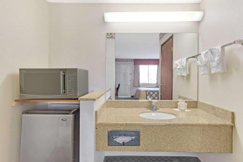 a bathroom with a sink and a tv and a mirror at Super 8 by Wyndham Tucson Downtown Convention Center in Tucson