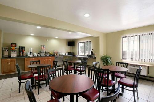 a restaurant with tables and chairs and a kitchen at Super 8 by Wyndham Eau Claire WI in Eau Claire