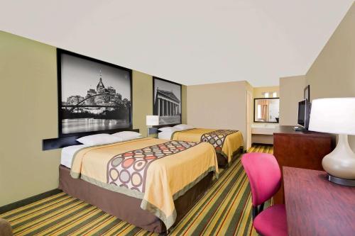 a hotel room with two beds and a tv at Super 8 by Wyndham Hermitage Nashville in Hermitage