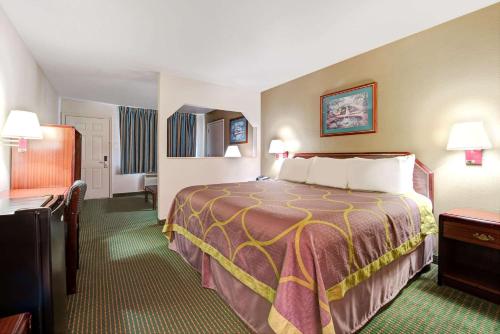 a hotel room with a bed and a desk at Super 8 by Wyndham Richardson Dallas in Richardson