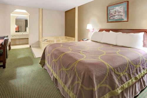 a hotel room with a bed and a bathroom at Super 8 by Wyndham Richardson Dallas in Richardson