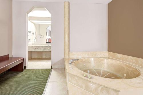 a large tub in a bathroom with a mirror at Super 8 by Wyndham Richardson Dallas in Richardson