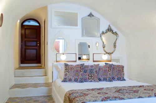 Un dormitorio blanco con una cama con almohadas azules. en Reflection Cave House, en Pirgos