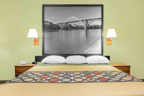 a bedroom with a bed with a picture of a bridge at Super 8 by Wyndham Eufaula in Eufaula