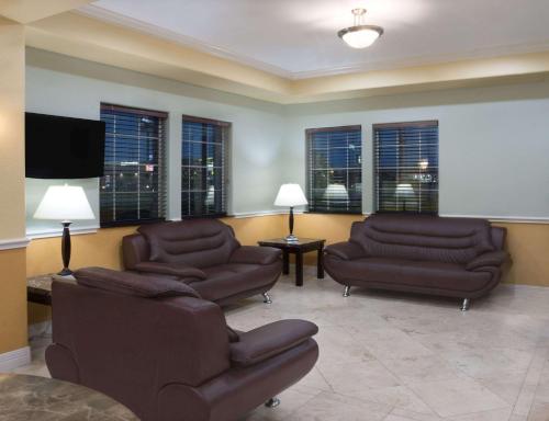 a living room with couches and chairs and windows at Super 8 by Wyndham Rosenberg TX in Rosenberg