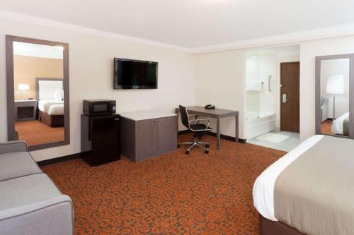 a hotel room with a bed and a desk and a television at Baymont by Wyndham Chicago/Alsip in Alsip