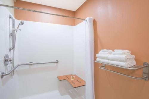 a bathroom with a shower with white towels at Days Inn & Suites by Wyndham Thibodaux in Thibodaux