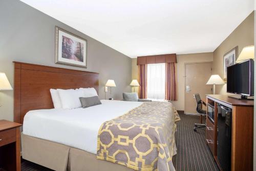 a hotel room with a bed and a flat screen tv at Baymont by Wyndham Hays in Hays