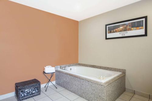 uma banheira num quarto com uma fotografia na parede em Days Inn & Suites by Wyndham Thibodaux em Thibodaux