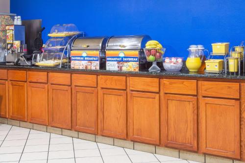 a kitchen counter with wooden cabinets and a blue wall at Days Inn & Suites by Wyndham Thibodaux in Thibodaux