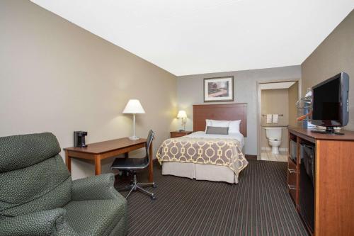 a hotel room with a bed and a desk and a television at Baymont by Wyndham Hays in Hays