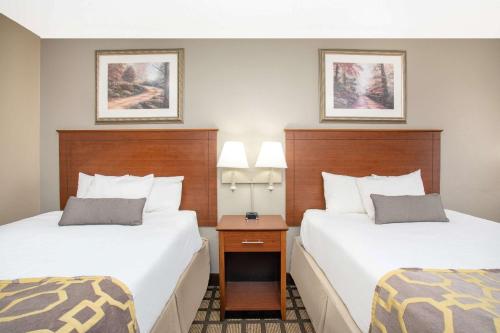 a hotel room with two beds and a night stand at Baymont by Wyndham Hays in Hays