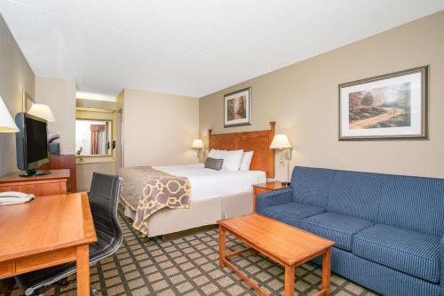 a hotel room with a bed and a blue couch at Baymont by Wyndham Hays in Hays