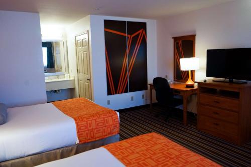 a hotel room with a bed and a desk and a television at Howard Johnson by Wyndham Salinas in Salinas