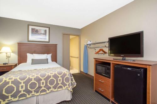 a hotel room with a bed and a flat screen tv at Baymont by Wyndham Hays in Hays