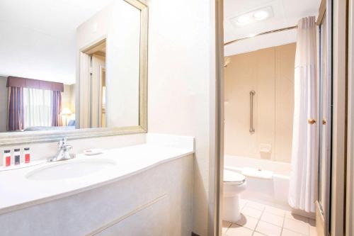 a bathroom with a sink and a toilet and a mirror at Baymont by Wyndham Hays in Hays