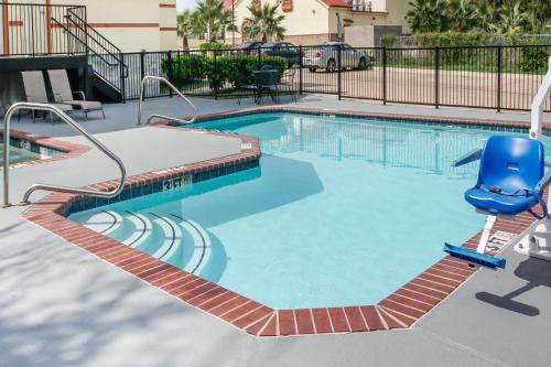una piscina con una silla azul en un apartamento en Super 8 by Wyndham Brenham TX, en Brenham