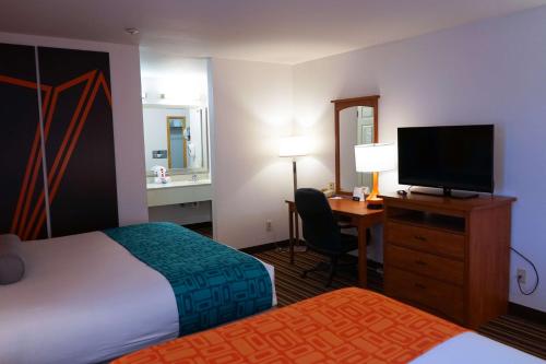 a hotel room with a bed and a desk with a television at Howard Johnson by Wyndham Salinas in Salinas