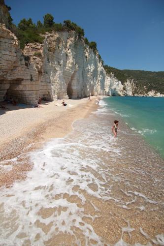 a beach with people swimming in the water at Residence Montelci in Mattinata