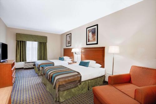 Habitación de hotel con 2 camas y sofá en Wingate by Wyndham Atlanta Fairburn, en Fairburn