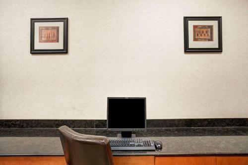 a computer on a desk with three pictures on a wall at Wingate by Wyndham Atlanta Fairburn in Fairburn