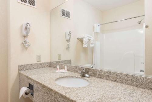 baño con lavabo con espejo y teléfono en Super 8 by Wyndham St Robert Ft Leonard Wood Area, en Saint Robert