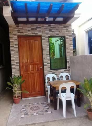 a patio with a table and chairs and a wooden door at 3Kid's Homestay Yellow in General Luna