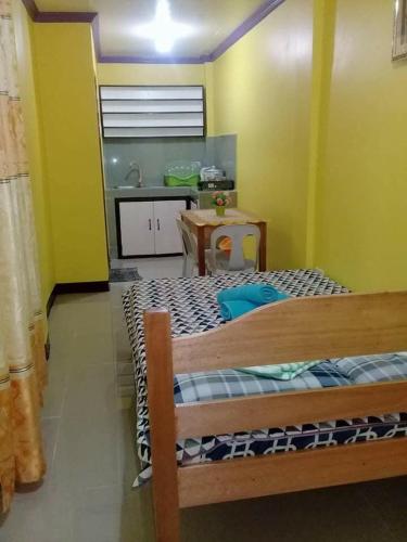 a bedroom with a bed and a kitchen with a table at 3Kid's Homestay Yellow in General Luna