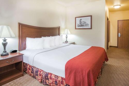 a hotel room with a large bed with a red blanket at Days Inn by Wyndham Ellis in Ellis