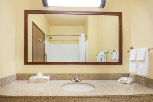 a bathroom with a sink and a large mirror at Days Inn by Wyndham Ellis in Ellis