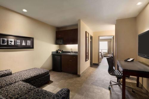 a hotel room with a bed and a desk and a kitchen at Days Inn by Wyndham Regina Airport West in Regina