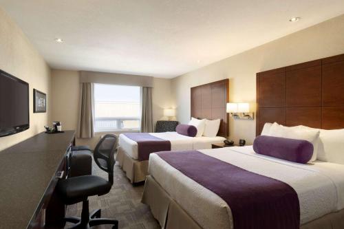 a hotel room with two beds and a television at Days Inn by Wyndham Regina Airport West in Regina
