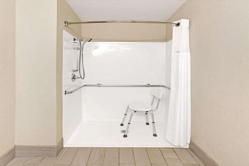 einen Stuhl im Bad mit Duschvorhang in der Unterkunft Baymont by Wyndham El Reno in El Reno