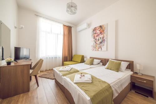 a bedroom with two beds and a desk and a television at Somnia in Bitola
