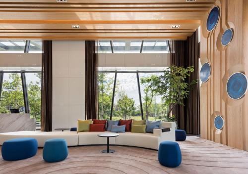 sala de estar con sofá blanco y sillas azules en Lakeshore Hotel Yilan en Yilan City