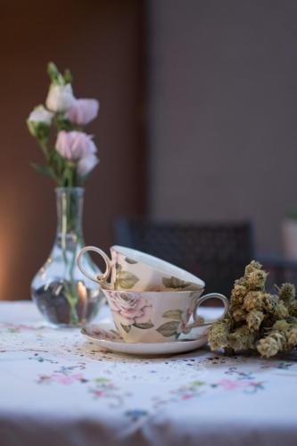 a cup and a plate on a table with a vase of flowers at Mythic Valley in Litochoro