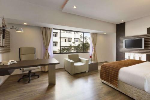 a hotel room with a bed and a desk and a computer at Ramada by Wyndham Chennai Egmore in Chennai