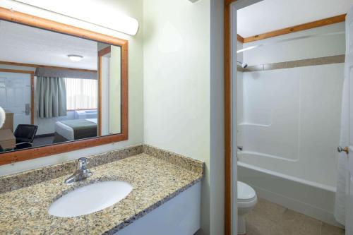 a bathroom with a sink and a mirror and a toilet at Travelodge by Wyndham Golden Sportsman Lodge in Golden