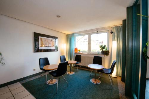 Habitación con 4 mesas, sillas y ventana en Hotel Residenz, en Schnelldorf