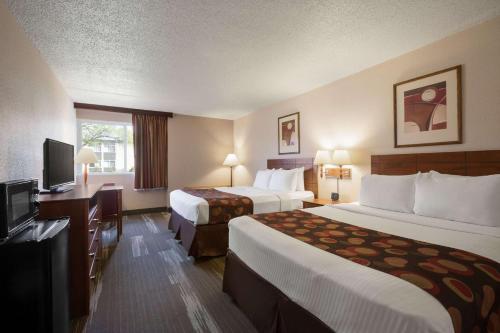 a hotel room with two beds and a flat screen tv at Ramada by Wyndham Bismarck in Bismarck