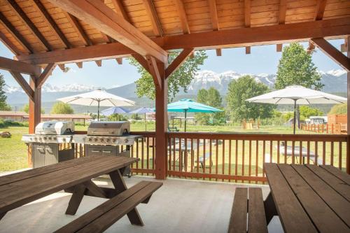 a patio with picnic tables and umbrellas and a grill at Travelodge by Wyndham Golden Sportsman Lodge in Golden